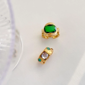 Detail view of retro gold rings featuring emerald cut green and purple gemstones