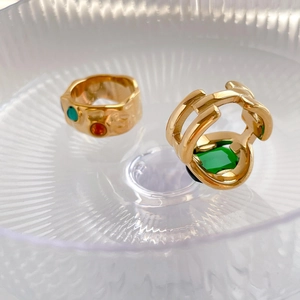 Detailed macro view of gold-tone rings featuring a textured band and an emerald gemstone