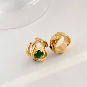 Detail of vintage gold-plated rings featuring hammered texture and emerald green gemstone