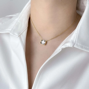 Close-up of square zircon pendant on a delicate gold chain worn by a female model