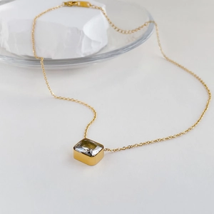 Detail of square zircon pendant on gold chain necklace with minimalist design