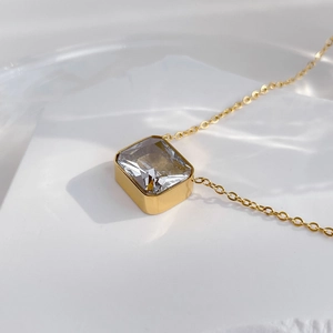 Macro shot of rectangular zircon pendant with gold bezel on delicate curb chain