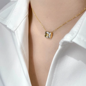 Close-up of elegant gold chain necklace with a square zircon pendant worn on a white shirt