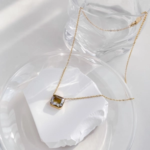 Detail of square zircon pendant on gold chain resting on white mineral stone