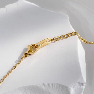 Macro shot of gold lobster clasp and K18 hallmark tag on delicate cubic zirconia necklace