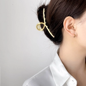 Minimalist gold metal hair claw clip and hoop earring set worn by a female model