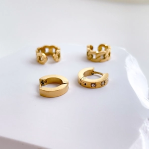 Close-up of four-piece gold star and chain link cuff earring set on a stone stand