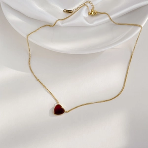 Close-up of 18K gold heart necklace with red enamel pendant and K18 hallmark detail