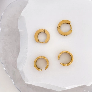 Detailed view of gold star chain ear cuffs and textured rings on stone surface