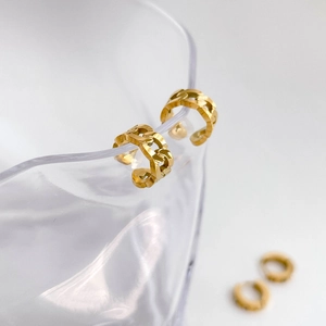 Golden chain link ear cuffs with hexagram charm shown hanging on a glass rim
