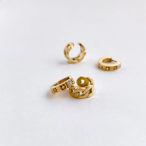 Golden star-patterned earrings and Cuban link ear cuffs set on white surface