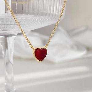 Romantic gold heart pendant necklace for women displayed on a striped glass vessel