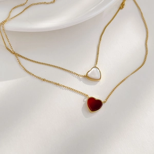Detail of gold heart pendant necklaces with red agate and white shell inlays