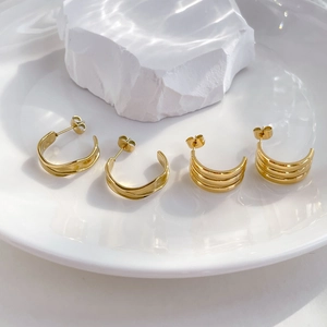 Minimalist gold plated triple-layer and wavy hoop earrings on a white aesthetic background