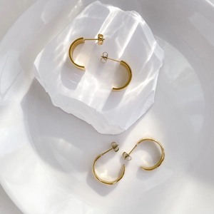 Detail of gold-plated triple-layer hoop earrings with polished finish and butterfly back