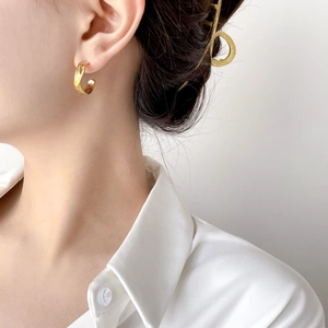 Detailed view of elegant gold C-shaped hoop earrings worn with matching geometric hair clip