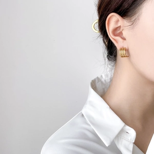 Detailed view of triple-layered gold hoop earrings worn by a model for a chic look