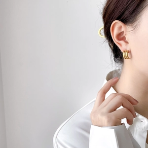 Detailed view of elegant triple-layered gold hoop earrings on female model