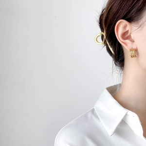 Detail view of a model wearing layered golden hoop earrings and a geometric hair clip