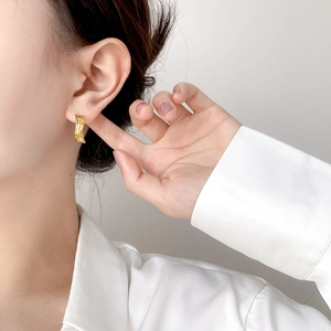 Close-up of gold twisted hoop earrings worn by a model in a minimalist style