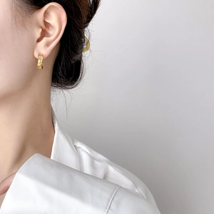 Detail of triple-layered golden hoop earrings with polished twisted design on model