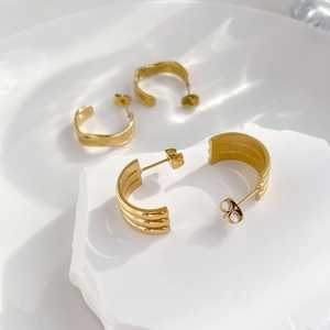 Detail of two pairs of gold C-shaped hoop earrings with smooth and triple-ribbed textures