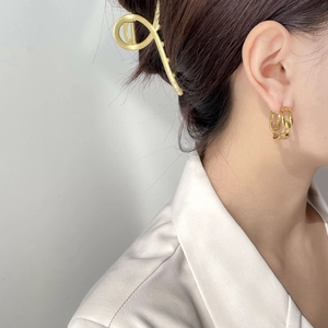 Nahaufnahme eleganter goldener Kettenohrringe und einer fließenden Haarspange