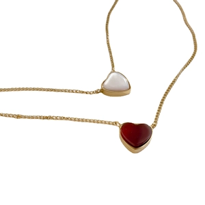 Minimalist gold heart necklace set featuring red and white pendants on a white background