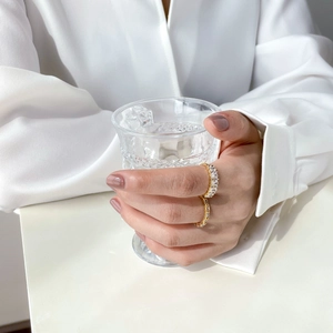 Close-up of elegant gold zircon rings worn on hand holding a crystal glass