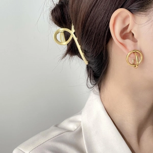 Nahaufnahme von minimalistischen Goldohrringen und Haarklammer an einer eleganten Frau