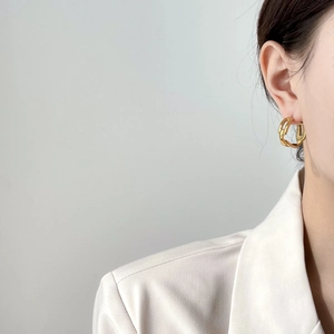Elegante goldfarbene verflochtene Ketten-Creolen für Damen an einem Model