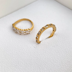 Close-up of two gold rings with micro-pave baguette zircon stones on white jewelry box