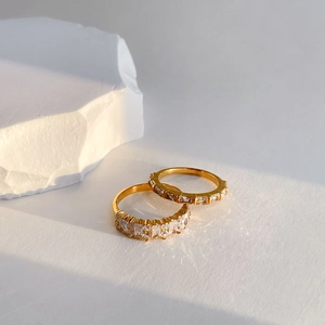 Minimalist gold rings with geometric zircon crystals on a clean stone background