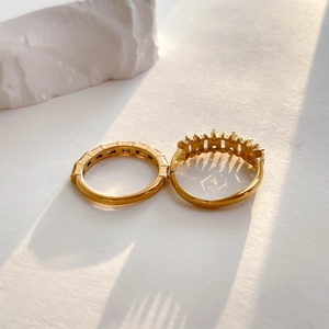 Close-up of gold zircon rings set with textured stone decor on a clean white backdrop