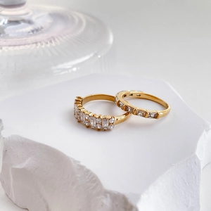 Macro shot of two gold-plated rings with zircon stones on a white natural stone base