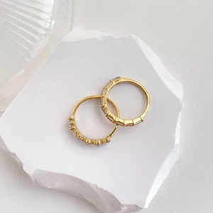 Macro view of gold plated zircon rings on white stone displaying luxury texture