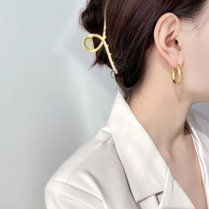 Gros plan de boucles d'oreilles goutte dorées et pince à cheveux minimaliste