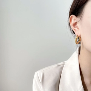 Boucles d'oreilles créoles dorées épaisses pour femmes portées avec un costume blanc chic