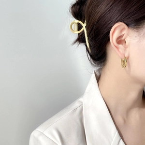 Gros plan sur une pince à cheveux dorée et des créoles minimalistes sur un mannequin