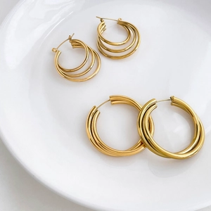 Macro detail of multi-layered gold hoop earrings in small and large sizes on a plate