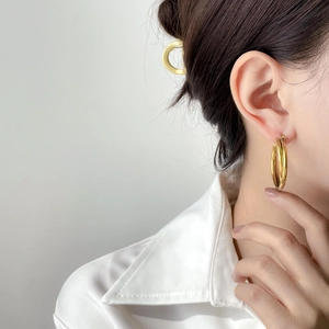 Close-up of golden multi-layer triple hoop earrings worn with white shirt