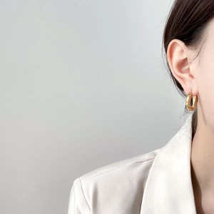 Boucles d'oreilles créoles dorées portées par un mannequin pour un look élégant