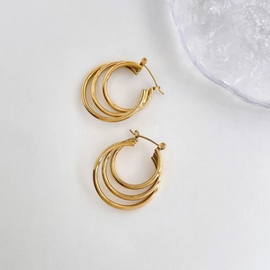 Close-up of golden multi-layer hoop earrings with a polished finish and triple ring design