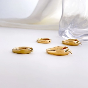 Gros plan de boucles d'oreilles losanges dorées avec une finition miroir très polie
