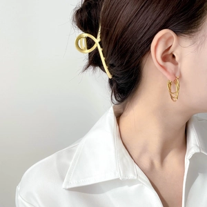 Close-up of golden multi-layered circular stud earrings on a model in a white shirt