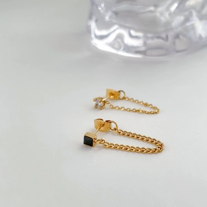 Close-up of gold chain earrings with square black zircon and clear crystal drops