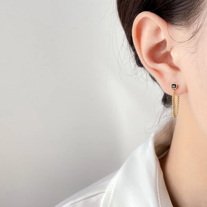 Detailed view of gold chain drop earrings with black zircon stone on model