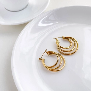 Detail shot of triple gold hoop earrings featuring a multi-layered geometric design