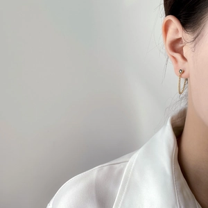 Detailed view of elegant gold chain earrings with black zircon stones worn by a model