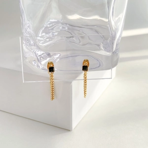 Macro detail of long gold chain earrings with black zircon stones on a display